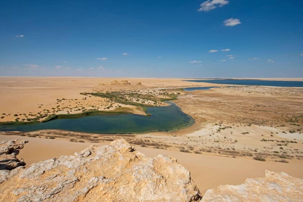 Panoramic aerial view over remote african egyptian desert landscape valley with oasis salt lake and pools