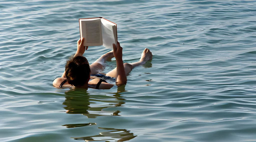 Dead Sea, Amman, Jordan A young girl in a bikini lying motionless on her back in the Dead Sea reading a book