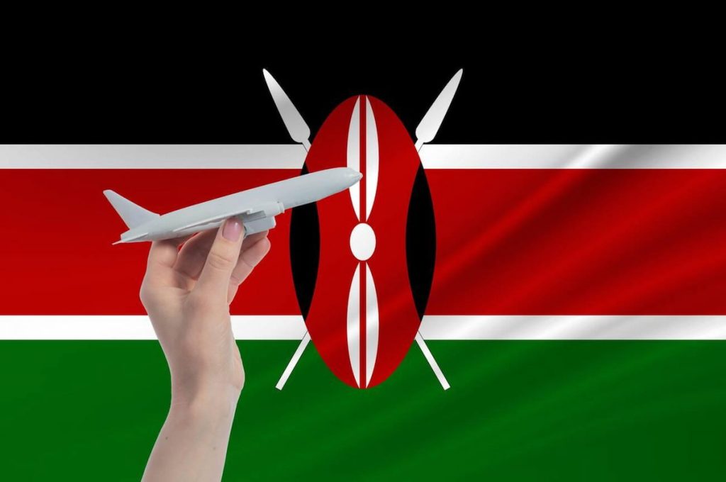 Airplane in hand with national flag of Kenya Travel to Kenya.