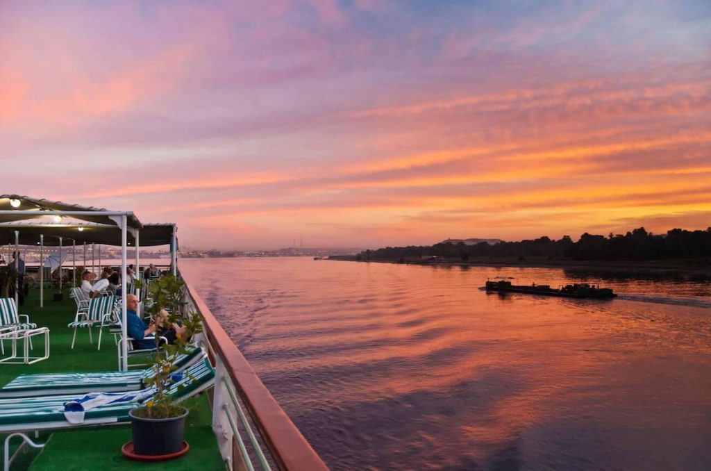 View of tourists relaxing on the upper deck of a cruise boat at sunset on the River Nile at Sunset Egypt Middle East