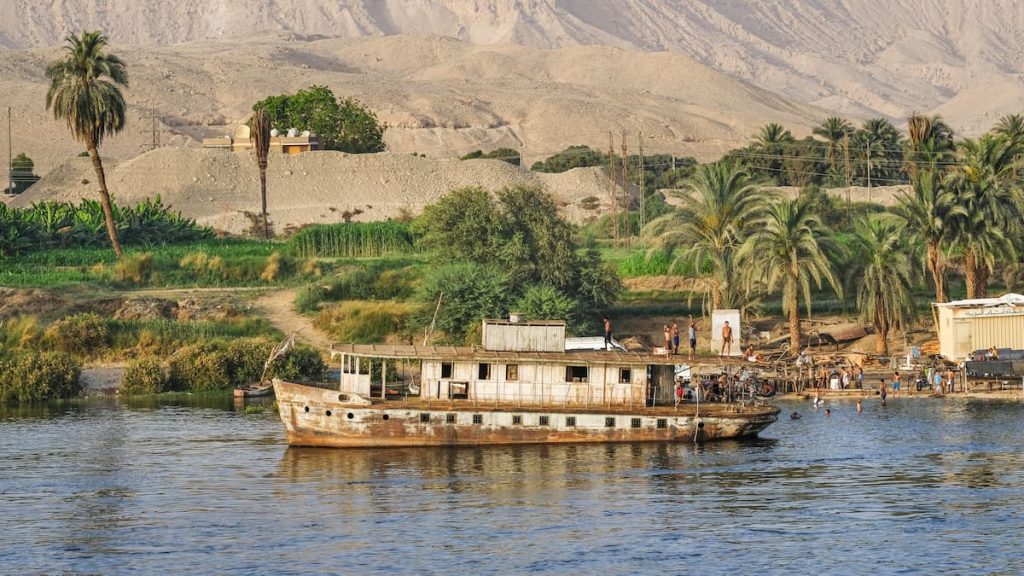 Old river ship and young Arabs bathing in river Nile, Egypt, ancient egyptian city names