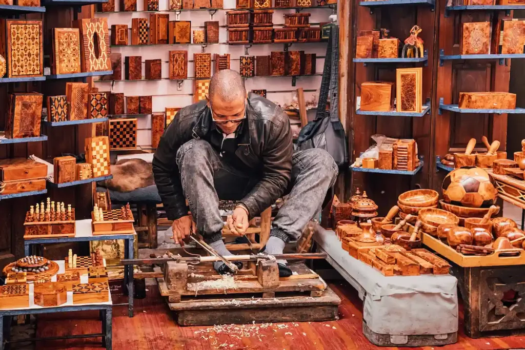 Moroccan artisan working wood with traditional tools, creating handcrafted souvenirs in a medina souk