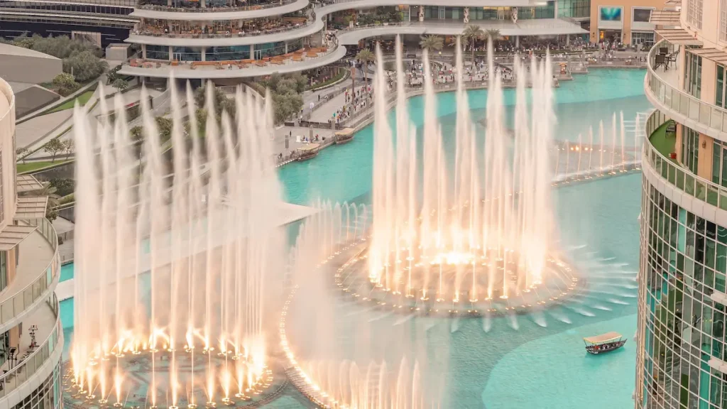 Dubai singing fountains with walking area around aerial . People watching show near shopping mall during sunset