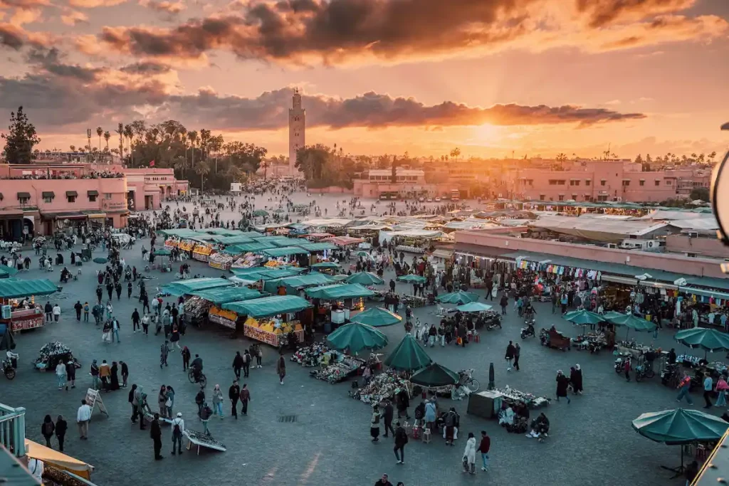 Marrakech, Morocco: Jamaa el Fna square filling up with people, food stalls and street vendors during a colorful sunset