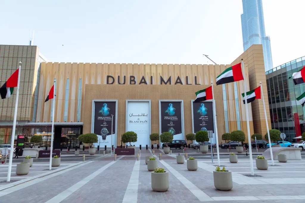 Entrance of the Dubai Mall with waving flags of United Arab Emirates on a flagpole