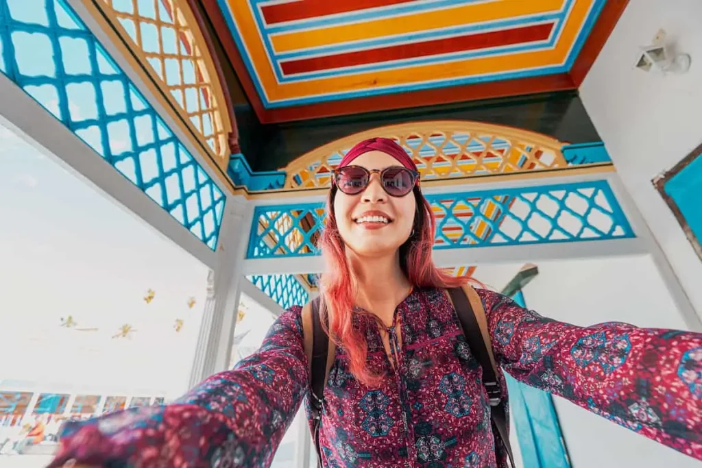 Young woman taking selfie with smartphone while visiting traditional arabic building