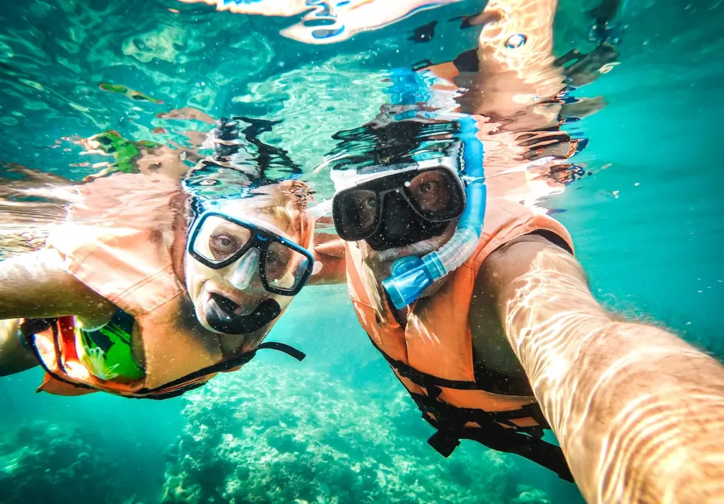 Active senior couple taking under water selfie in tropical sea excursion with water camera