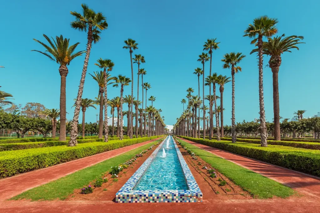 Scenic view of the manicured hedges, palm trees, and water features creating a peaceful oasis in the Arab League Park in Casablanca