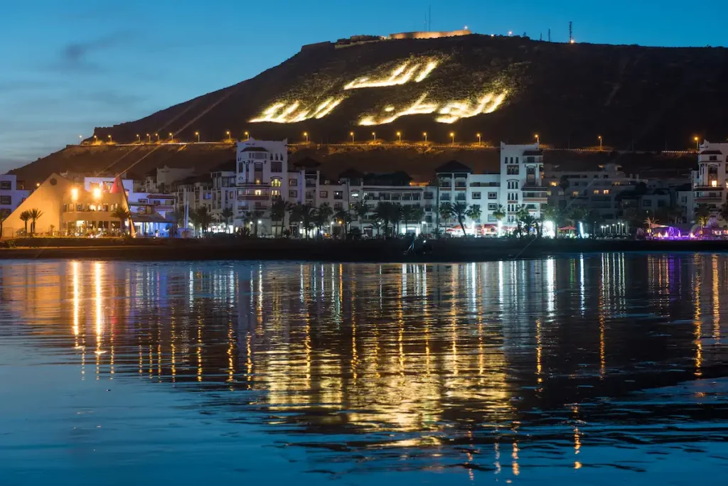 Sea front view of Agadir marina at night with reflection in the water, Morocco