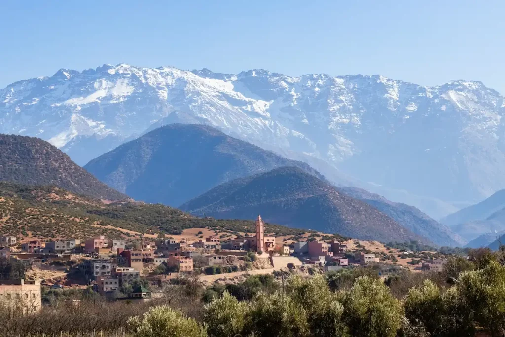 Grand Atlat mountains and Orica valley view with traditional houses and mosque minaret snowy mountains on background Morocco