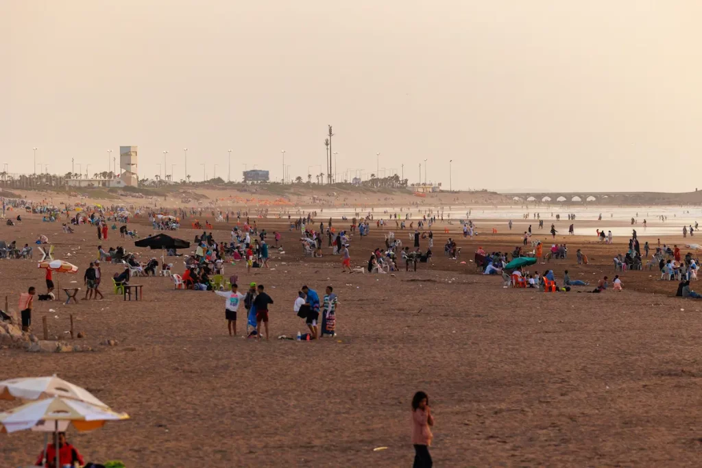 Tourists and local people enjoy Ain Diab Beach at sunset in Casablanca, Morocco