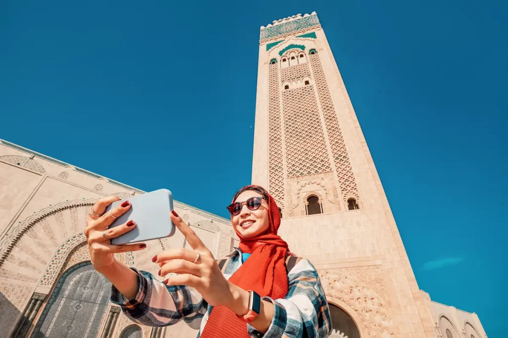 Young woman tourist taking selfie with smartphone in front of Hassan II Mosque in Casablanca, Morocco