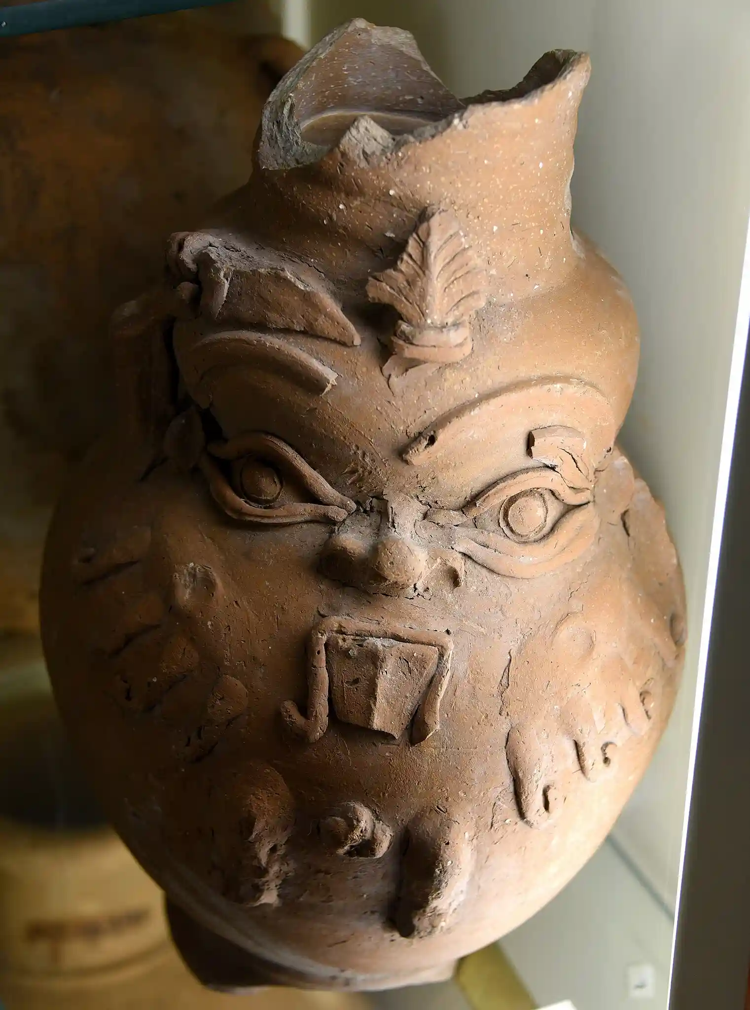 Pottery vessel. Applique face of god Bes on surface