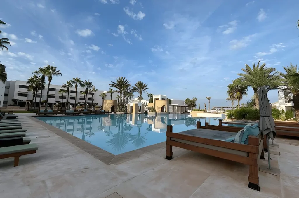View of the Sofitel hotel swimming pool with palm trees, sun loungers, and clear skies, highlighting the resort’s luxury design and tranquil atmosphere.
