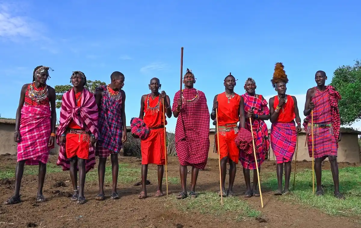 MAASAI MARA NATIONAL RESERVE, KENYA, AFRICA - NOVEMBER 11, 2022: Group of Maasai men in traditional clothes singing a song about a successful lion hunt in the middle of a maasai village in Kenya, Africa