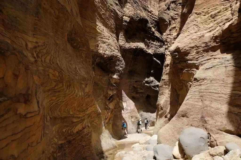 Dana Biosphere Reserve in Jordan. Amazing rocks in Wadi Ghuweir Canyon. Silhouette of hiking people on trail. 