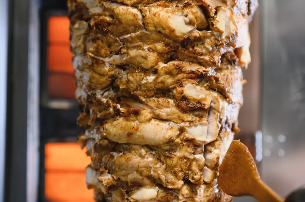 Juicy chicken shawarma rotating on a spit, being cooked and ready to be served as a delicious street food