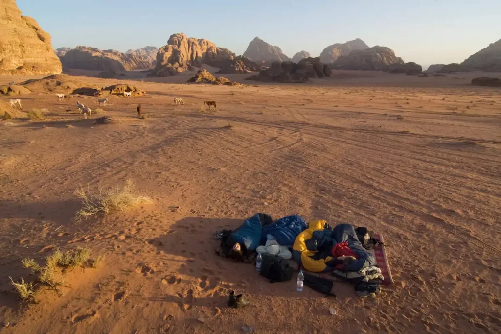 Tourists sleeping in a sleeping bag under an open sky in the desert, Wadi Rum, Jordan, Middle East